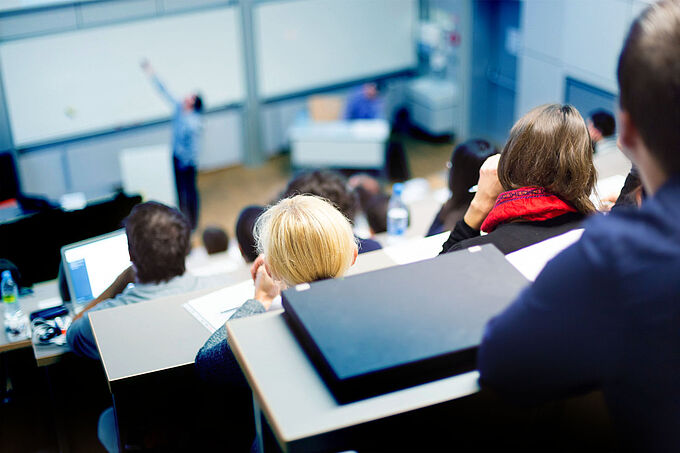 Speaker giving presentation in lecture hall at university. Participants listening to lecture and making notes. Speaker giving presentation in lecture hall at university. Participants listening to lecture and making notes.